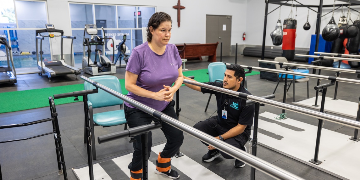 A woman doing sitting exercises in a gym, guided by a male physical therapist