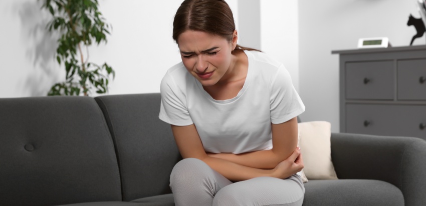 Young woman suffering from cystitis on sofa at home